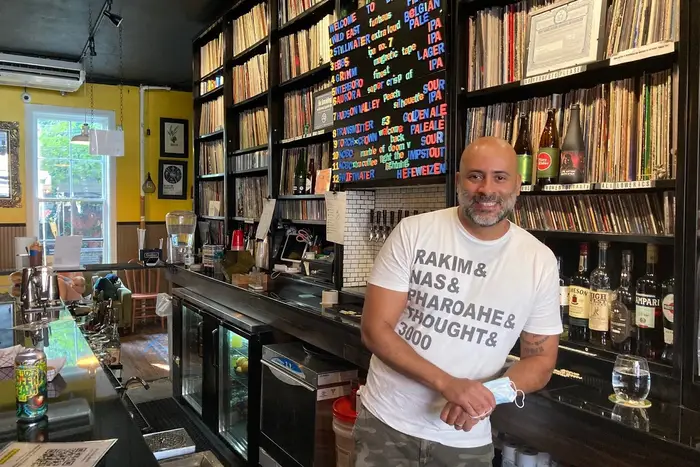 Chris Maestro, one of the owners of Bierwax in Prospect Heights stands in front of a vast record collection behind his bar.